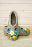 Pair of felted slippers with floral designs on a wooden surface