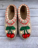 Woolen house shoes with cherry embroidery for women and men on the gray wooden floor.