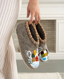 Pair of gray woolen slippers with decorative designs held by a person indoors.