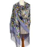 Decorative wrapping scarf with floral patterns and fringes on a white background made of sheep wool and silky fringe.
