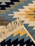 Close-up of a geometric patterned rug with fringes.