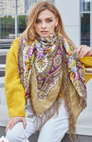 Woman wearing a colorful patterned scarf and yellow sweater outdoors.