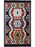 A square flatweave area Armenian ethnic  rug with a traditional geometric kilim pattern in red, black, cream, light blue, and tan. Traditional Armenian ethno style textile country style house carpet. Close-up shot of a durable cotton acrylic blend flat-weave rug featuring beige and ivory tribal motifs.