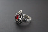 A set of Armenian sterling silver 925 jewelry including earrings and a ring with a pomegranate shape and red garnet cabochon.
