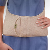 A beige waist support belt worn by a model in a blue ribbed top.