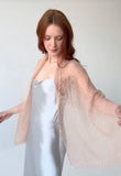 Beige lace shawl made of premium knitted goat down wool, showcasing its delicate, semi-sheer openwork pattern and narrow rectangular shape on a woman shoulders.