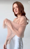 An ultra-lightweight, beige goat down pashmina shawl laid out flat to highlight its gossamer-thin woolen lace design and delicate, scalloped borders on a woman`s shoulders.