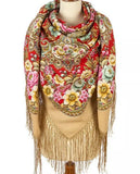 Colorful floral-patterned red and beige woolen large scarf with fringe on a mannequin against a white background. Close-up detail focusing on the soft, high-quality texture of a red merino wool scarf swatch. The thick, dark red fabric is printed with an elaborate arrangement of multicolored flowers, highlighting its cozy and classic winter aesthetic.