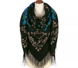 Black and blue floral-patterned wrapping scarf with fringe on a mannequin against a white background