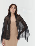 A narrow rectangular woolen black pashmina styled as a lightweight scarf, its delicate, lace-like texture visible on a woman`s shoulders.