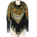 Black fringed scarf with mustard floral patterns and black fringes on a mannequin against a white background