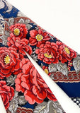 Close-up of a floral patterned blue merino wool shawl with red flowers on a blue background