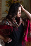 Woman wearing a patterned merino wool scarf with a blurred floral background
