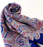 Colorful blue paisley patterned cozy travel blanket scarf on a white background