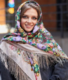 Woman wearing a colorful floral beige and brown headscarf with vintage purple and pink peony flowers and fringe details.