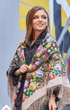 Woman wearing a colorful floral-patterned merino wool beige and brown shoulders shawl with purple and pink vintage peony flowers.