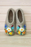 Pair of felted wide chuni slippers with floral designs on a wooden surface