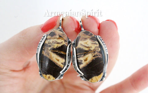 Handcrafted with care and expertise, this Armenian jewelry piece features a stunning coconut jasper design in shades of yellow and brown. The unique oval shape is created using high-quality sterling silver, making it truly one of a kind. Elevate your style with this exquisite and handcrafted accessory.
