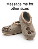 Pair of brown woolen slippers with decorative elements on a white background