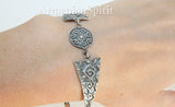 Silver bracelet with geometric patterns, displayed against a woman`s wrist.