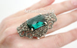 A large silver Victorian-style ring with faceted green topaz and Marcasite embellishments, on  a hand.