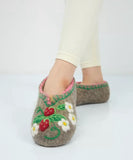Felted slippers with strawberry design worn by a person on a white background