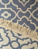 Close-up of a blue and beige patterned rug with fringe