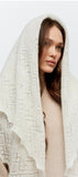 Handmade ecru goat down pashmina woolen shawl draped softly over a woman head to contrast its delicate, snowy ivory hand-knitted pattern. The light hitting the fabric highlights the gossamer-thin premium texture.