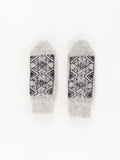 Gray woolen knit mittens with Nordic snowflakes ornament in black on a white surface.