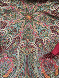 Close-up of a colorful paisley pattern shawl in Slavic style with soft olive green paisley patterns and yellow ethnic ornaments.