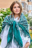 Woman wearing a green patterned blanket size woolen scarf outdoors