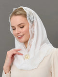 A woman wearing a white lace-trimmed headscarf for church and a cream-colored top, shown in a close-up portrait against a solid gray background.