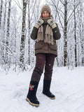  A detailed view of premium, handcrafted Slavic winter boots showcasing a wide-shaft design worn over patterned beige wool socks and brown textured trousers. The right boot features a prominent artisan-stitched floral and berry motif in vibrant red, white, and silver tones.
