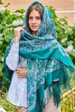 Woman wearing a teal patterned scarf outdoors with greenery in the background