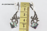Pair of earrings with a central gemstone measurement against a ruler.