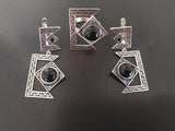 Armenian silver jewelry set with geometric designs and black stones on a dark background