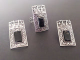 A set of silver ring and earrings with black gemstones and Armenian taraz ornaments on a gray background