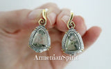 Teardrop-shaped earrings with silver and gold accents held in a hand, branded 'Armenian Spirit'.