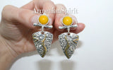 Silver earrings with yellow stones held by a hand on a white background, branded 'Armenian Spirit'.
