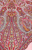 Colorful paisley patterned merino wool palatine with a brand label on a pink background