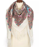 Decorative milky white scarf with floral pale blue and pale pink floral patterns and fringes on a mannequin against a white background