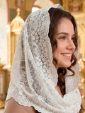 A woman wearing a white lace Orthodox veil with delicate flowers in a golden-domed church interior. 