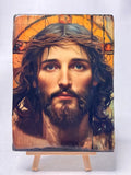 Handcrafted 13x17 cm wooden icon of Jesus Christ with a crown of thorns on a miniature easel. Realistic portrait painting of Jesus with a glowing gold leaf halo printed on a thick wood block.  Devotional Catholic artwork of Christ's face with a textured faux-gesso finish and rustic edges.