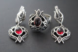 A set of Armenian oxidized sterling silver 925 jewelry including earrings and a ring with a pomegranate shape and red garnet cabochon.