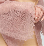 Gossamer dusty pink knitted shawl draped over shoulders. Lightweight winter pashmina shawl in dusty pink with lace like woolen knitting.