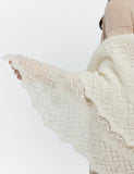 A side profile shot of a woman shoulder  wrapped warmly in the ecru winter wrapping shawl. This cozy lifestyle goat down palatine perfectly conveys cold-weather comfort and insulation.