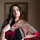 Woman wearing a patterned woolen scarf in a room with a painting on the wall.