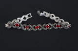 A woman bracelet with marcasite and red oval gemstones made of 925 silver on a black surface.