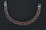 A silver bracelet with red stones and Marcasite patterns, displayed against a black background.