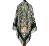 Vintage blanket shawl in dark green with blue and yellow floral patterns and fringes on a white background